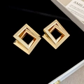 Makro-Detail von geometrischen 3D-Ohrringen aus poliertem vergoldetem Metallquadrat - Gold