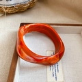 Detail of translucent orange marble acrylic bangle with irregular wave design in tray - Orange - Twisted
