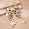 Detalle de pendientes en forma de pez con escamas de nácar y ojos azules sobre piedra - Dorado