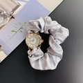 Detail of silver satin scrunchie watch band with golden round dial on dark background - Gray