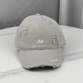 Close-up of distressed light gray baseball cap with 'N' embroidery on marble surface - Light Gray