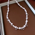 Detail van parelketting met verloopkralen en klaverhangers op een lederen dienblad - Roze Wit