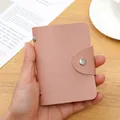 Pink faux leather anti-RFID card holder with snap button closure held in hand - 24 Slots / RFID Pink