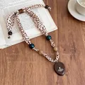 Dettaglio della collana retrò in tessuto leopardato con perline di legno e ciondolo pianeta - 11# Collana-Caffè-Globo di Saturno