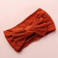 Detail view of caramel knitted baby headband featuring a large bow and soft cable textures - Orange Red