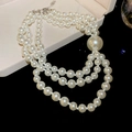 Detail view of a triple-strand pearl necklace with large focal pearl in a velvet box - Three-Layer White Pearl Necklace