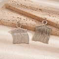 Macro detail of elegant silver metal tassel earrings on a textured stone surface - Silver