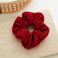 Close-up of red Christmas scrunchie with metallic glitter sequins on fabric - Red