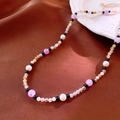 Detailed close-up of handmade beaded necklace with purple and pearl beads on silk - Purple