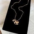 Detail view of gold-plated lucky coin and rocking horse pendants on a black velvet pillow - Copper / Rocking Horse Copper Coin Necklace (HN11099-1) / Gold