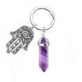Detail der Hamsa-Hand und violetter sechseckiger Kristall am silbernen Schlüsselanhänger - Amethyst