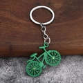 Close-up of green alloy bicycle keychain with small rhinestones on a textured background - Green