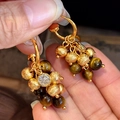 Detail van tijgeroog en gouden kralen oorbellen met sprankelende zirkonia accenten - Retro Tijgeroog Cluster Kwastje Stijl / Goud