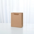 Thick brown kraft paper gift bag with dark ribbon handles and a minimalist design - Medium Vertical Style
