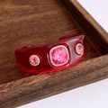 Makroaufnahme der roten Harzspange mit quadratischem rosa Kristall und Pavé-Strass - Roter Armreif Mit Rosenrotem Stein