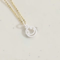 Minimalist gold necklace with a white smiley face pendant and serrated edge design - White