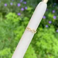 Detailed close-up of a 18K gold plated bow-shaped ring with zircons on a white display stand - Butterfly Knot Style