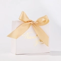 Close-up of a white wedding favor box with a gold silk bow and Thank You lettering - White Box + Gold Ribbon