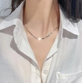 Detailed view of layered silver snake bone chains on a white shirt worn by a female model - Herringbone Chain / Silver