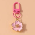 Gros plan du porte-clés fleur de cerisier rose avec bordure dorée et fermoir mousqueton - Rose