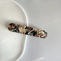 Detail of amber tortoiseshell hair clip with delicate golden bead flower patterns - Black Coffee