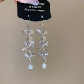 Detalle de pendientes de flores plateadas con perla colgante y acabado metálico S1000 - Gancho de Oreja de Flor Plateada