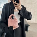 Mini borsa a secchiello intrecciata rosa tenuta da una modella con camicia di raso nero - Rosa