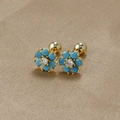Macro de boucles d'oreilles fleurs turquoise avec fermoir doré sur tissu texturé - Or-Bleu Lac