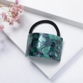 Detailed close-up of dark green marble patterned acetate hair ring with elastic band - Green