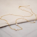 Long gold chain necklace featuring natural white freshwater pearls on a linen background - Single Starry Pearl Style