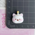 Top view of a small resin white cat figurine with a birthday hat on a metric cutting mat - White Birthday Hat Puppy