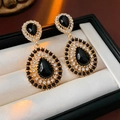 Dettaglio di orecchini vintage dorati con pietre nere e cristalli in una scatola - Stile Pendente Nero (Ago in Argento) / Nero