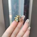 Golden beetle brooch with colorful rhinestones held by a hand in natural light - Multi-color