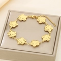 Close-up of golden flower charms bracelet with lobster clasp on jewelry display case - Flower Shape Style (KB187931-NT)