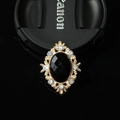 Detailed macro view of vintage gold alloy brooch with black oval gemstone and rhinestones - Black Gemstone