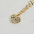 Exquisite goldene Herz-Halskette mit Mikro-Pave-Kristallen auf weißem Lederhintergrund - Kleines goldenes Herz