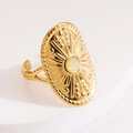 Close-up of vintage adjustable gold ring featuring sunburst relief and green stone inlay - Milky White