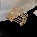 Makro-Detail des goldfarbenen mehrlagigen offenen Armreifs mit hohlem Panzerketten-Muster - Mehrlagiger hohler offener Stil / Gold