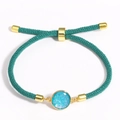 Detail of adjustable blue braided cord bracelet with a sparkling blue round charm inlay - Stone Green