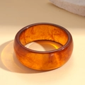 Detail van een brede barnsteen hars armband met marmeren textuur en gepolijst - Ronde Stijl / koffiekleur