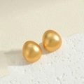 Dettaglio macro di orecchini dorati a forma di uovo con texture in metallo spazzolato - Sfera Opaca / Sfera d'Oro
