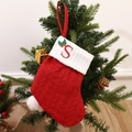 Red knitted Christmas stocking with white cuff and embroidered letter S on festive tree - Letter S