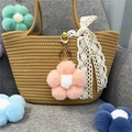 Close-up detail of a pink plush flower bag charm attached to a woven straw summer bag - 1 Piece / Pink