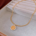 Macro-opname van een tweekleurige muntketting in een grijze fluwelen sieradendoosje - Retro Goud-Zilver Tweekleurige Muntstijl