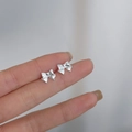 Minimalist 925 silver bow stud earrings shown held in hand for size perspective - Large Bowknot / Silver
