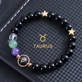 Macro detail of Taurus zodiac bracelet with 8mm obsidian beads on a textured background - Taurus