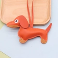 Close-up of bright orange dachshund leather pendant with detailed stitching and lychee texture - Dachshund / Orange