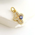 Macro detail of gold-plated cross pendant with white zircon and blue evil eye bead - Blue Eye Cross