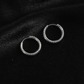 Detalle de pendientes de aro retorcidos en acero de titanio plateado sobre terciopelo negro - Aro Torsado / Color acero
