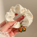 Detailed close-up of floral scrunchie with orange fruit charms and soft white fabric - Persimmon Charm Style / Light Yellow Floral